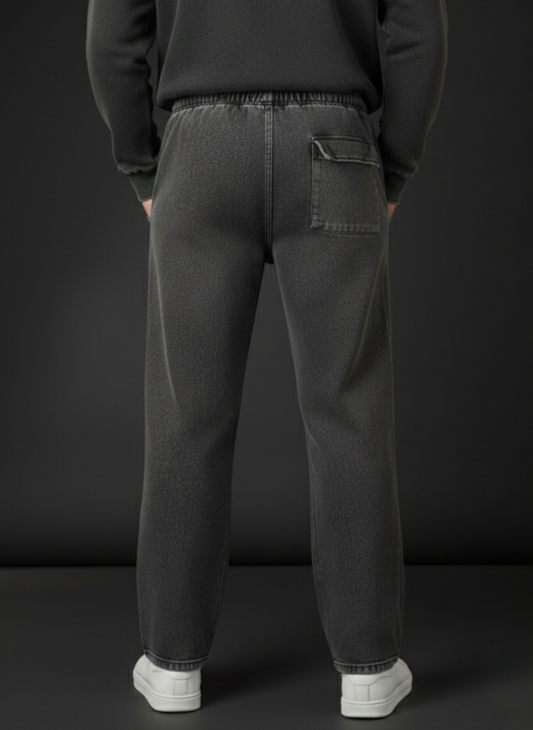 Person wearing dark gray sweatpants with a plain black background