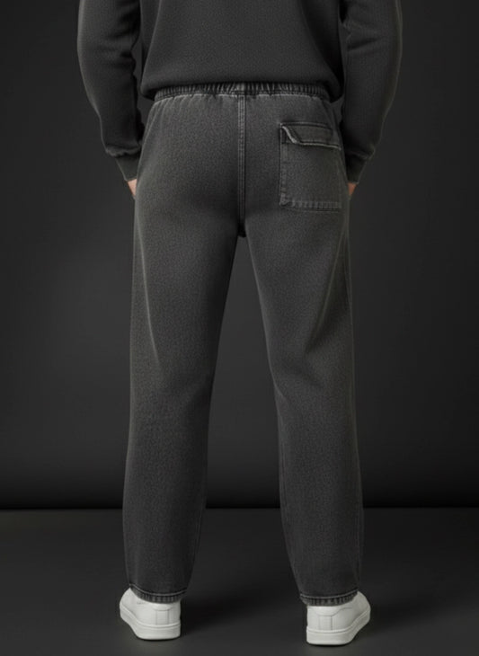 Person wearing dark gray sweatpants with a plain black background