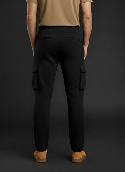 Person wearing black cargo pants and tan shoes on a dark background