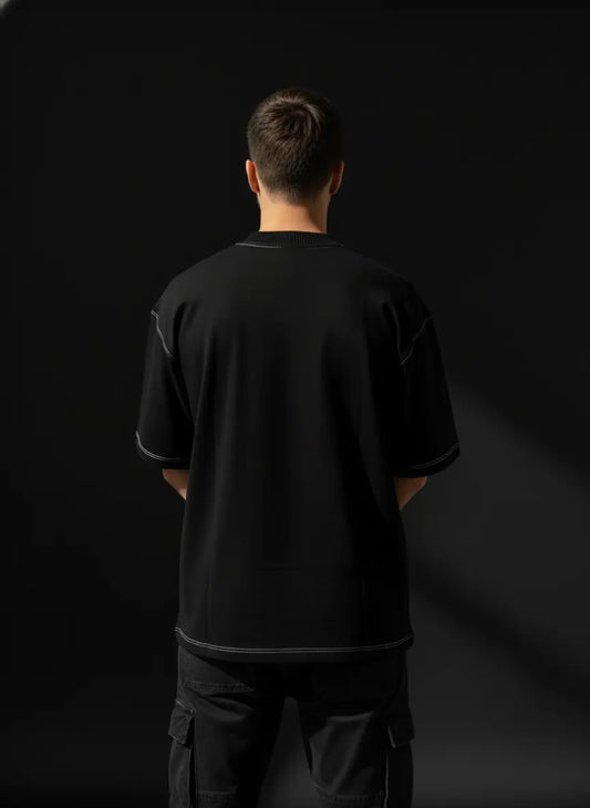 Person wearing a black t-shirt and pants against a black background