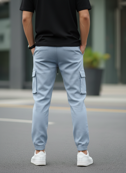 Person wearing light blue cargo pants and a black shirt on a blurred street background