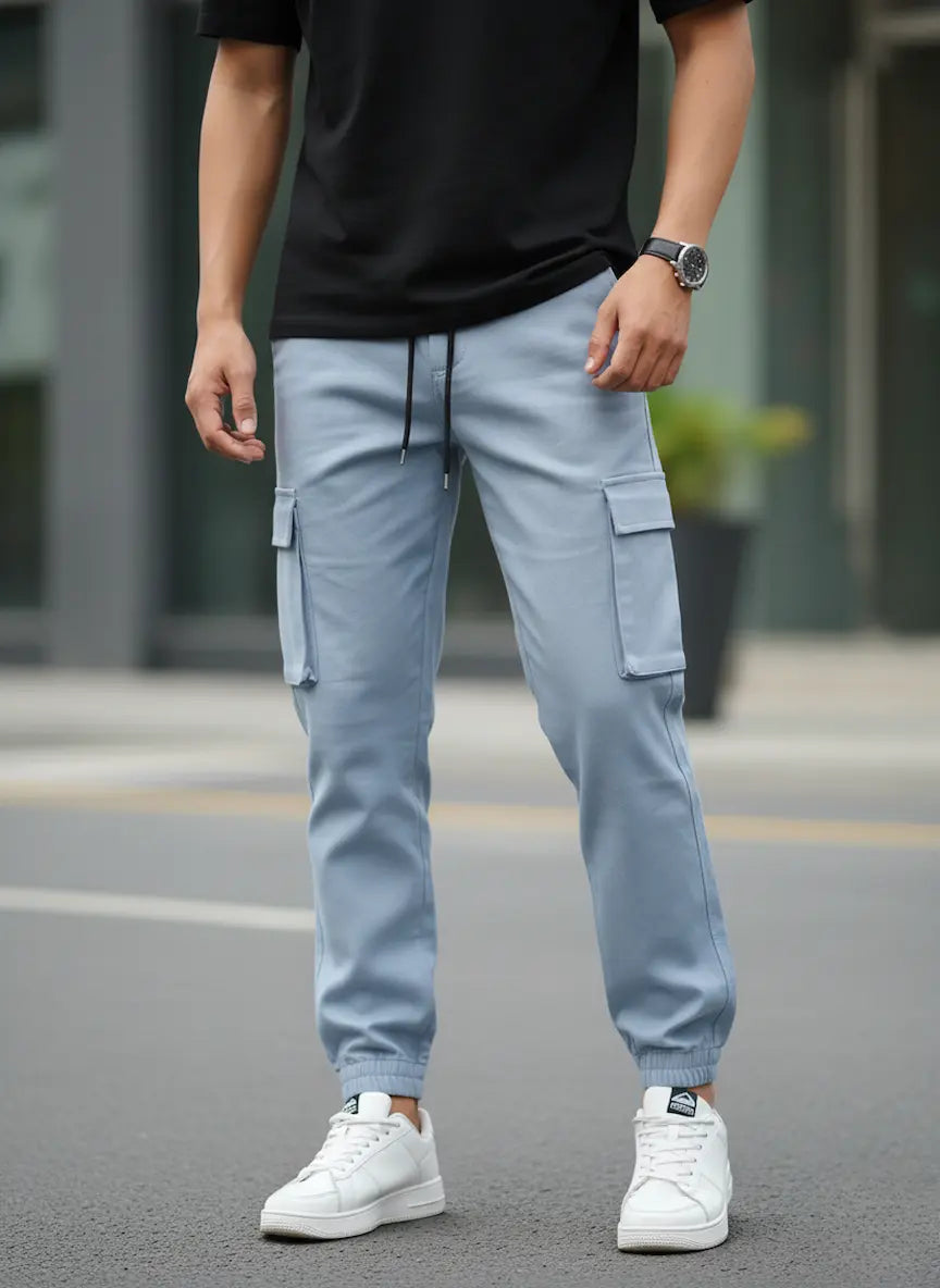 Person wearing light blue cargo pants and white sneakers on a street.