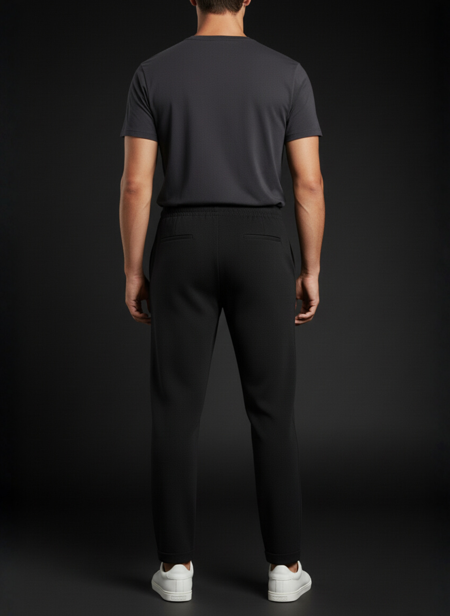 Person wearing a dark gray t-shirt and black pants on a black background