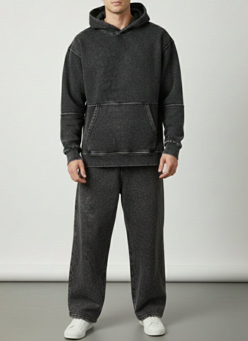 Person wearing a dark gray hoodie and pants on a plain background