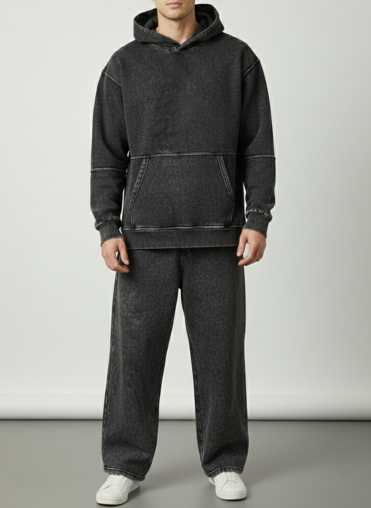 Person wearing a dark gray hoodie and pants on a plain background