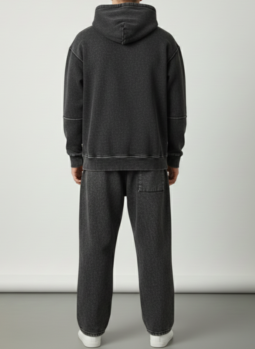 Person wearing a dark gray hoodie and pants on a plain background