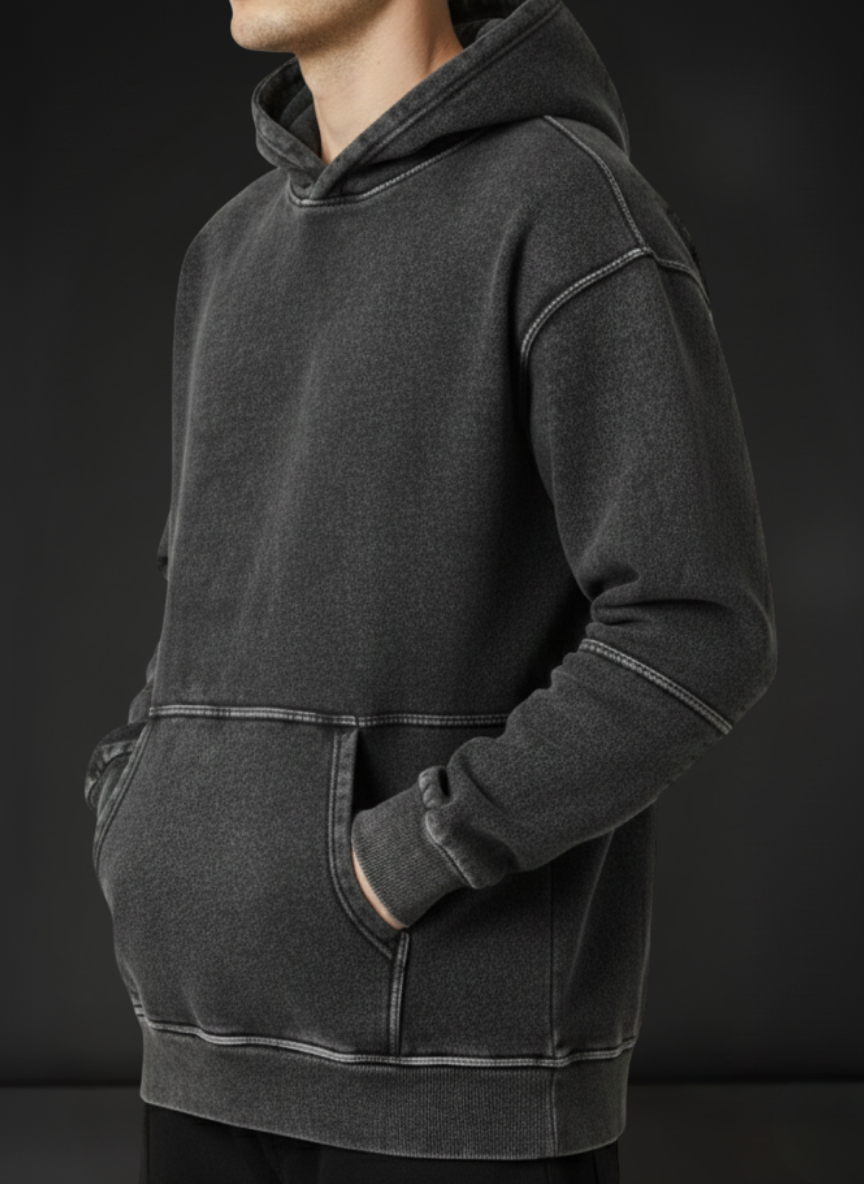 Person wearing a dark gray hoodie against a black background