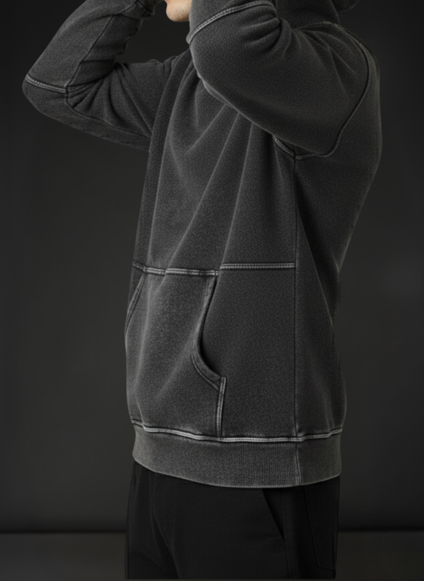 Person wearing a dark gray hoodie against a black background