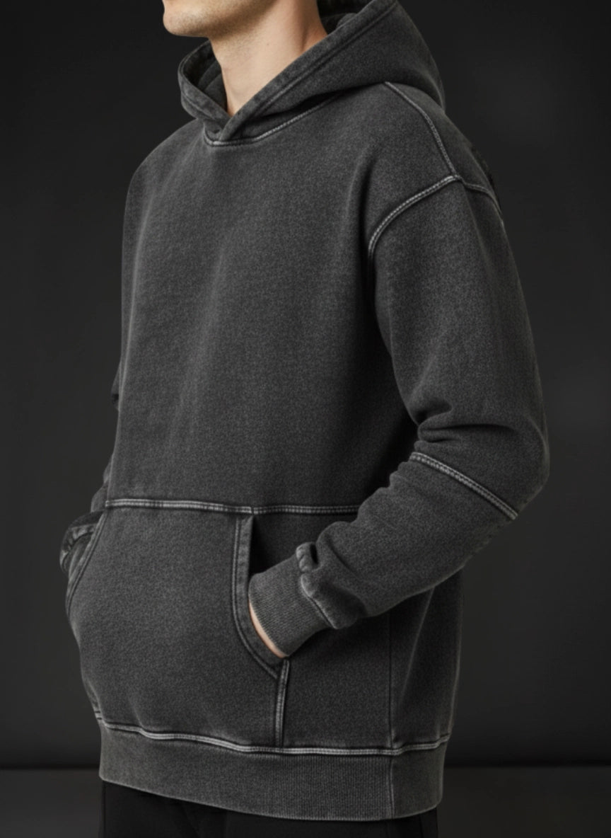 Person wearing a dark gray hoodie against a black background