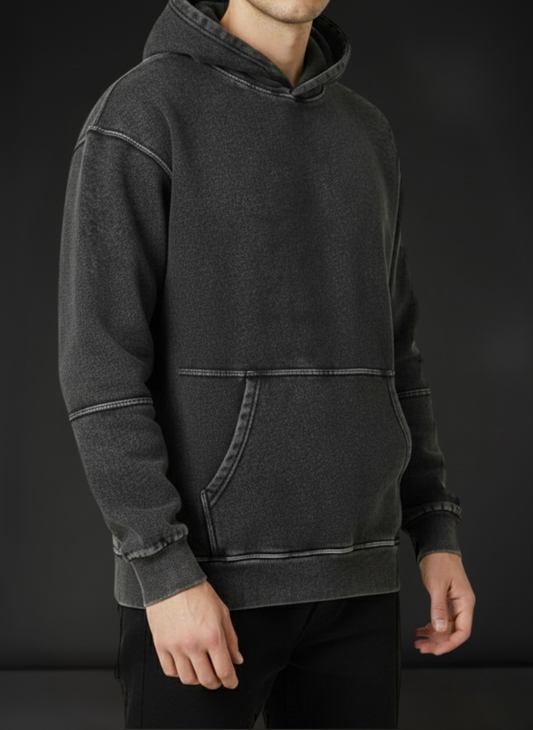 Person wearing a dark gray hoodie against a black background