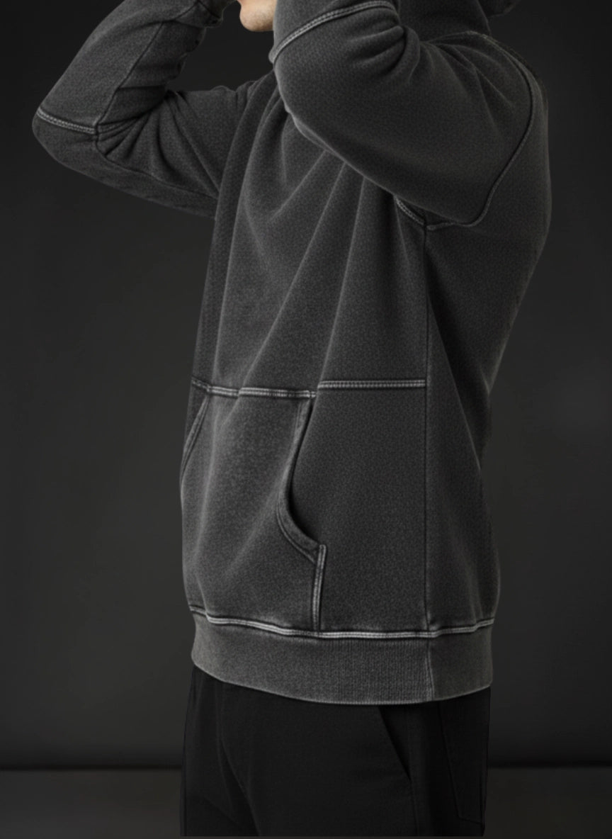 Person wearing a dark gray hoodie against a black background