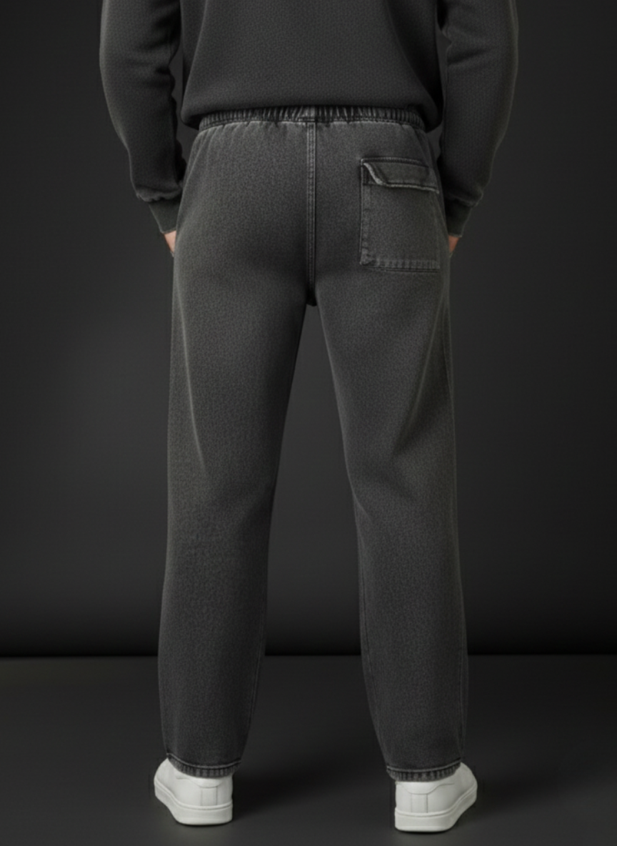 Person wearing dark gray sweatpants with a plain black background