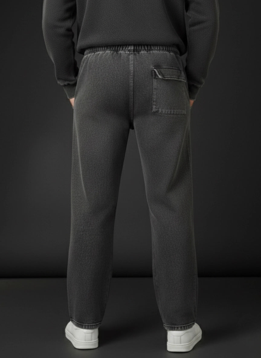 Person wearing dark gray sweatpants with a plain black background