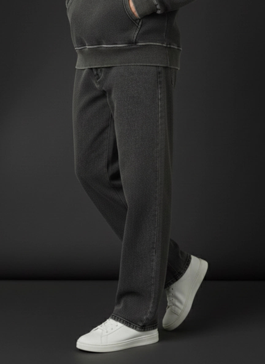 Person wearing dark trousers and white sneakers on a black background