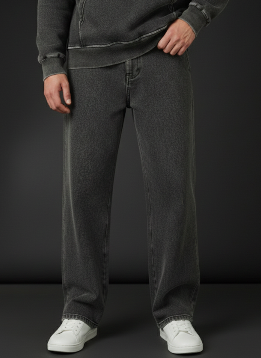 Person wearing dark gray jeans and white sneakers on a black background