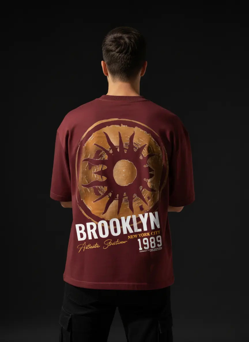 Person wearing a red t-shirt with 'Brooklyn' and sun design on a black background