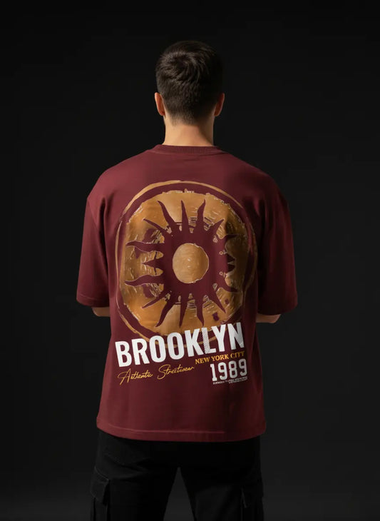 Person wearing a red t-shirt with 'Brooklyn' and sun design on a black background