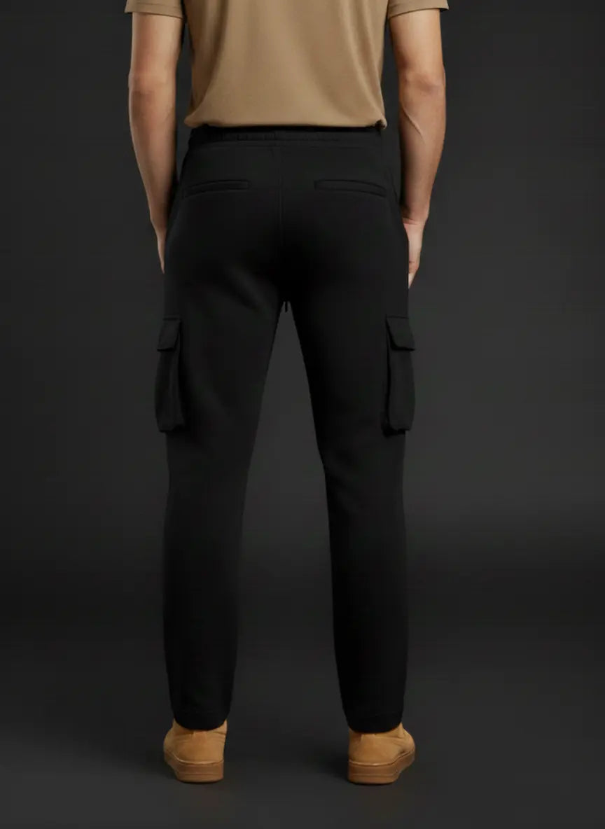 Person wearing black cargo pants and tan shoes on a dark background
