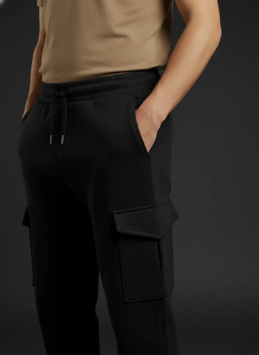 Person wearing black cargo pants with a plain background