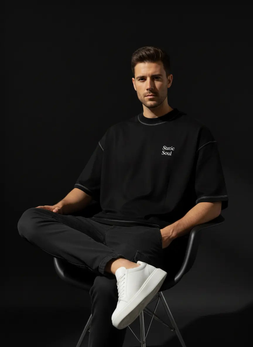 Man sitting in a black chair wearing a black outfit with 'Stark' branding on a dark background