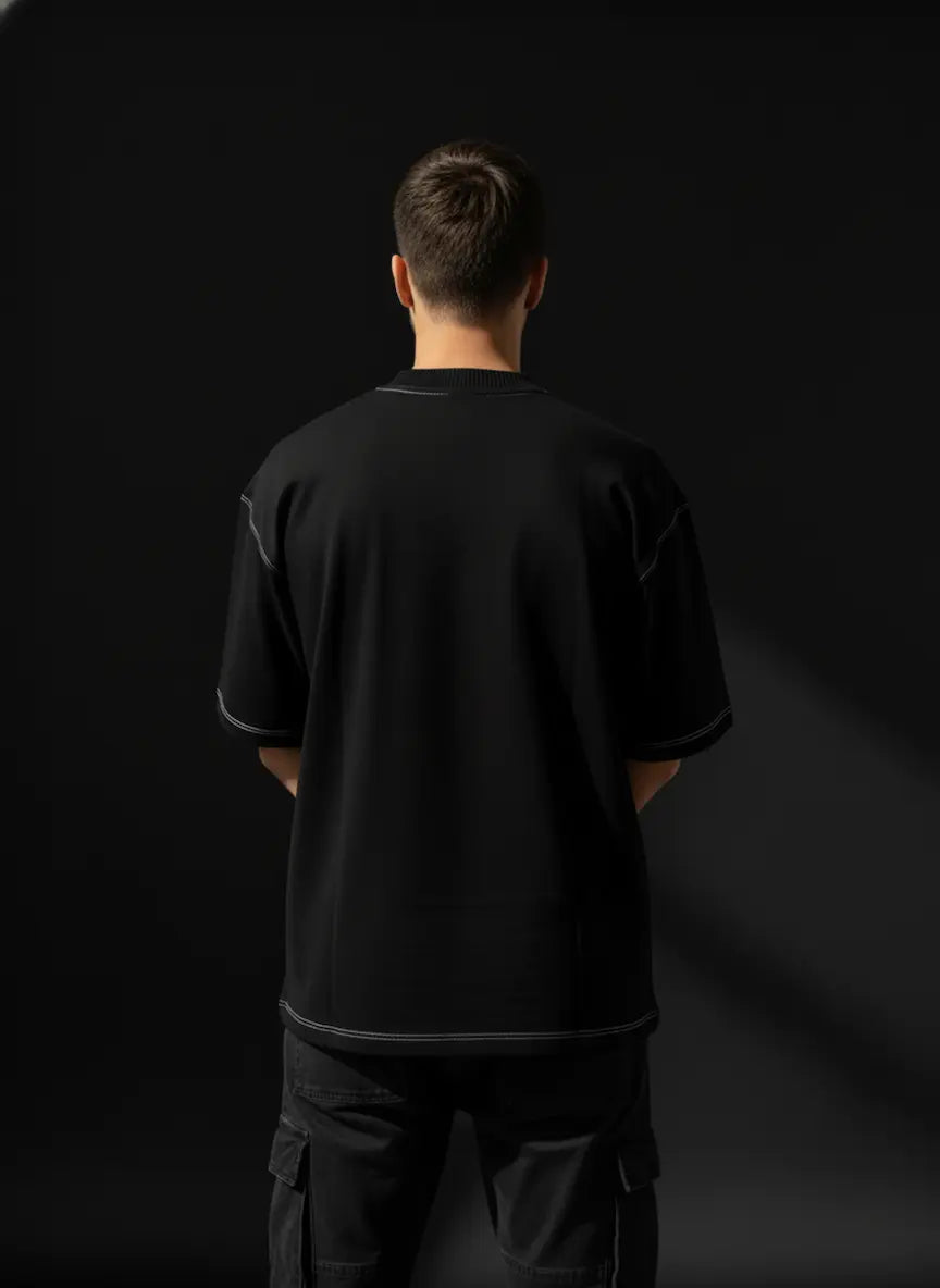 Person wearing a black t-shirt and pants against a black background