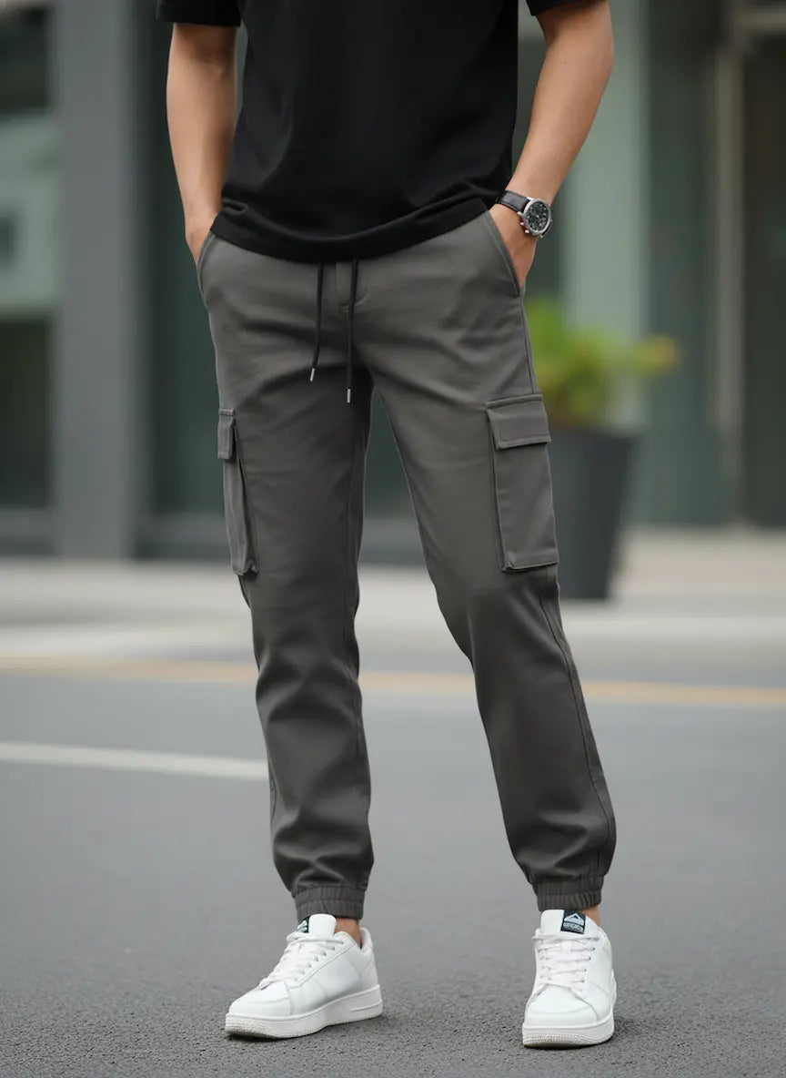 Person wearing Charcoal Drift Cargo Trouser and white sneakers on a blurred street background