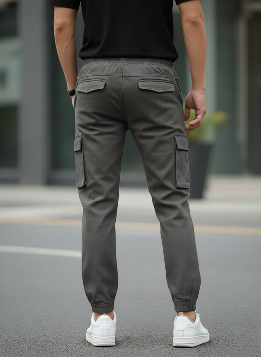 Person wearing gray cargo pants and white sneakers on a street.