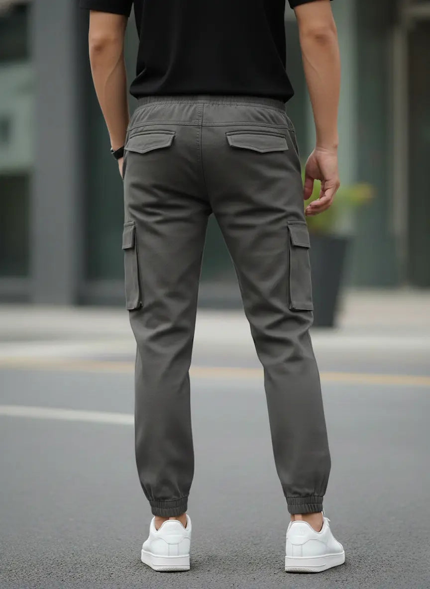 Person wearing gray cargo pants and white sneakers on a street.