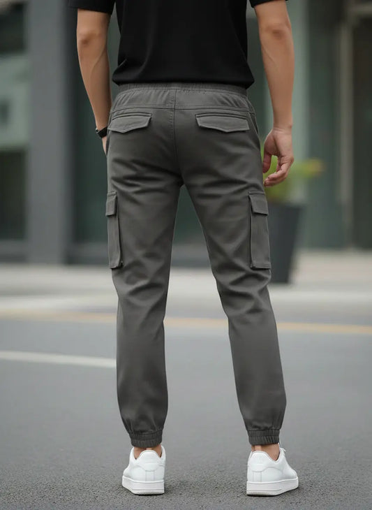Person wearing gray cargo pants and white sneakers on a street.