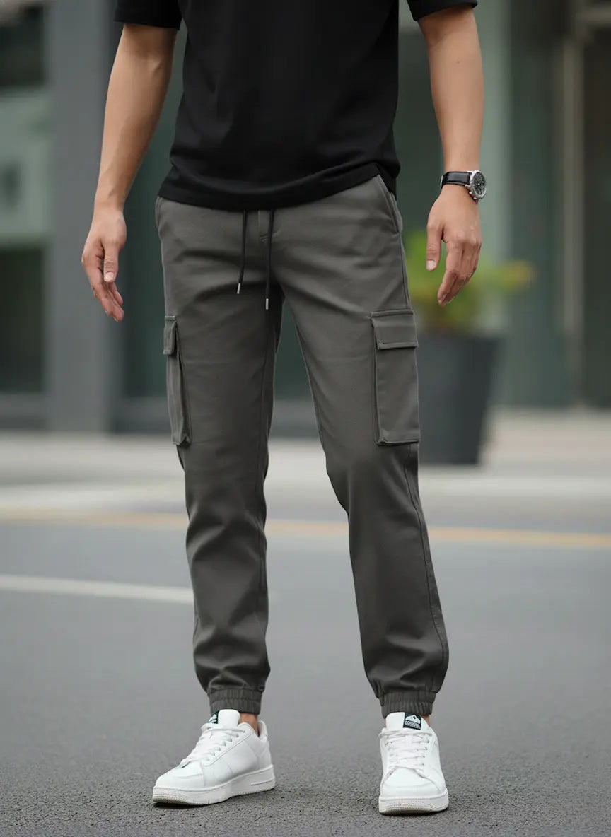 Person wearing gray cargo jogger pants and white sneakers on a street.