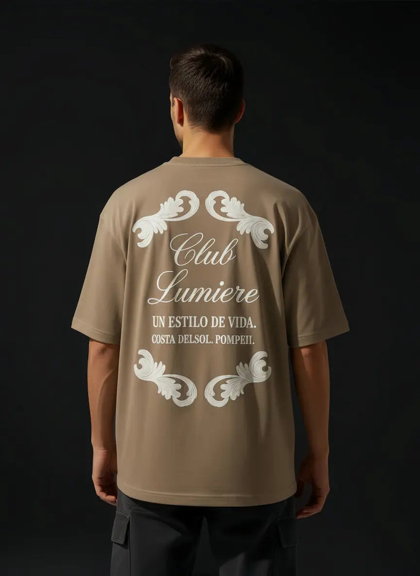 Man wearing a brown t-shirt with 'Club Lumiere' design on the back against a black background