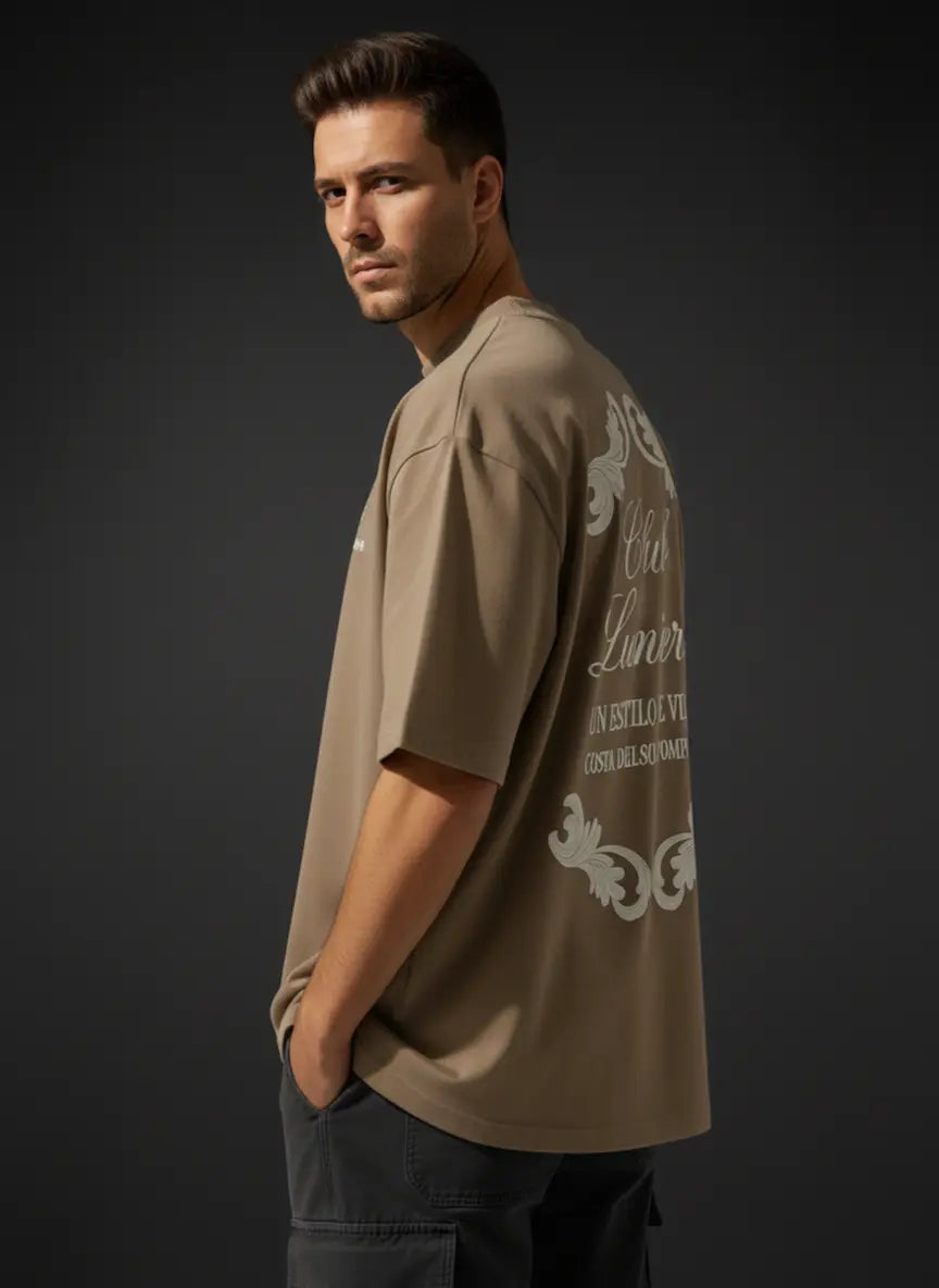 Man wearing a CLUB LUMIERE Oversized Cotton T-Shirt with white text and graphics on a dark background