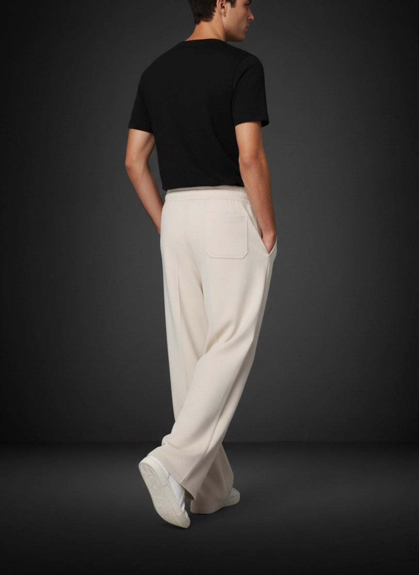 Person wearing a black t-shirt and beige pants against a dark background