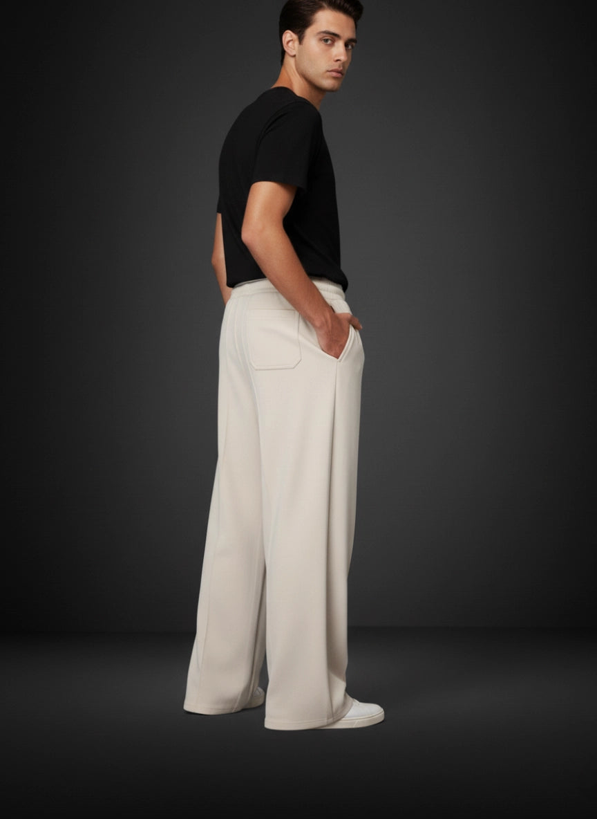 Man wearing a black shirt and white pants against a dark background