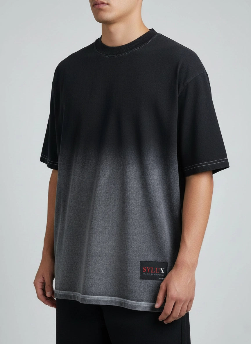 Person wearing a black and gray gradient t-shirt with a brand logo on a light gray background