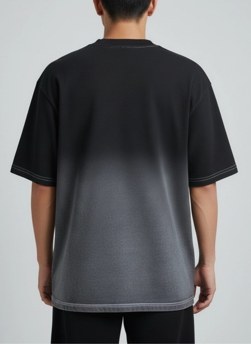 Person wearing a black to gray gradient t-shirt on a plain background