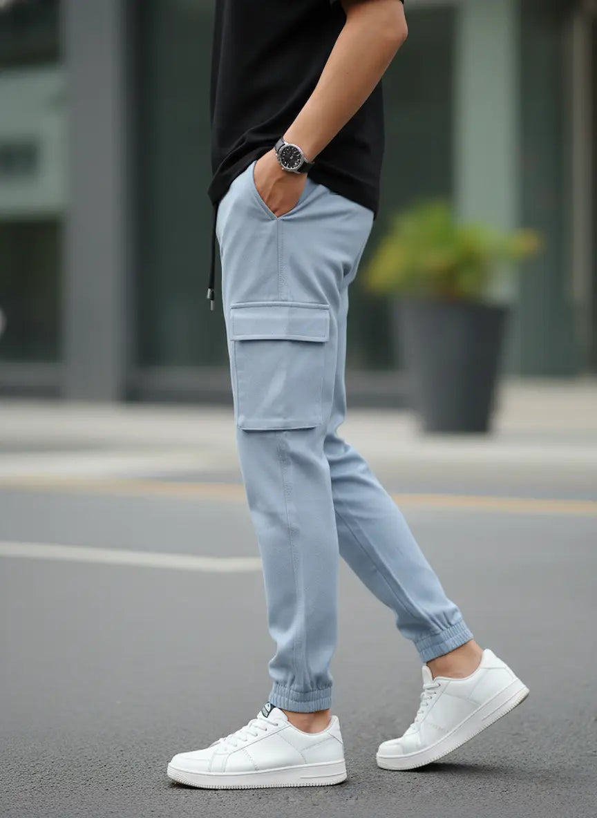 Person wearing light blue cargo pants and white sneakers on a blurred street background