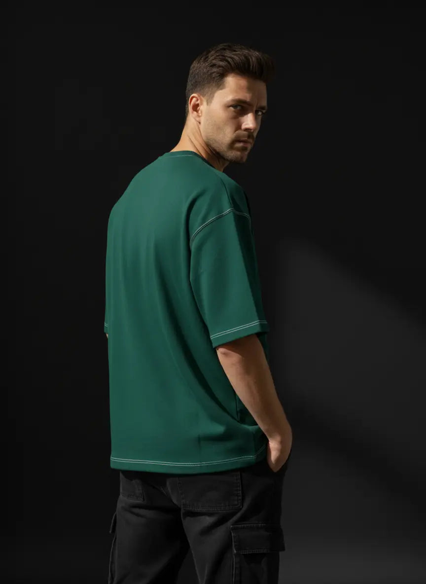 Man wearing a green t-shirt and dark pants against a black background