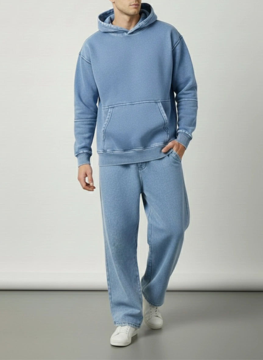 Person wearing a blue tracksuit with white shoes on a plain background