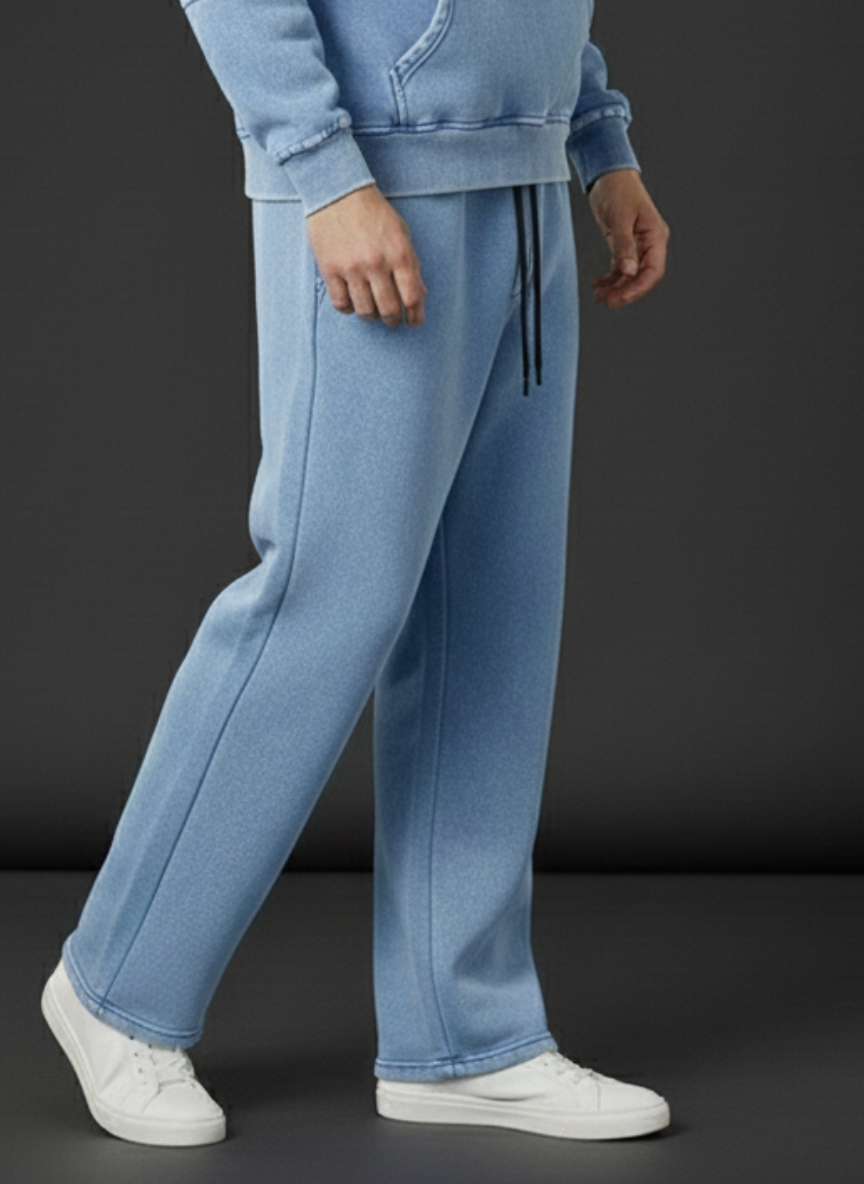 Person wearing light blue tracksuit with white sneakers on a dark background