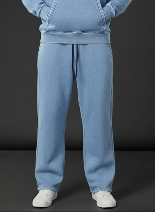Person wearing a light blue tracksuit with white shoes on a dark background