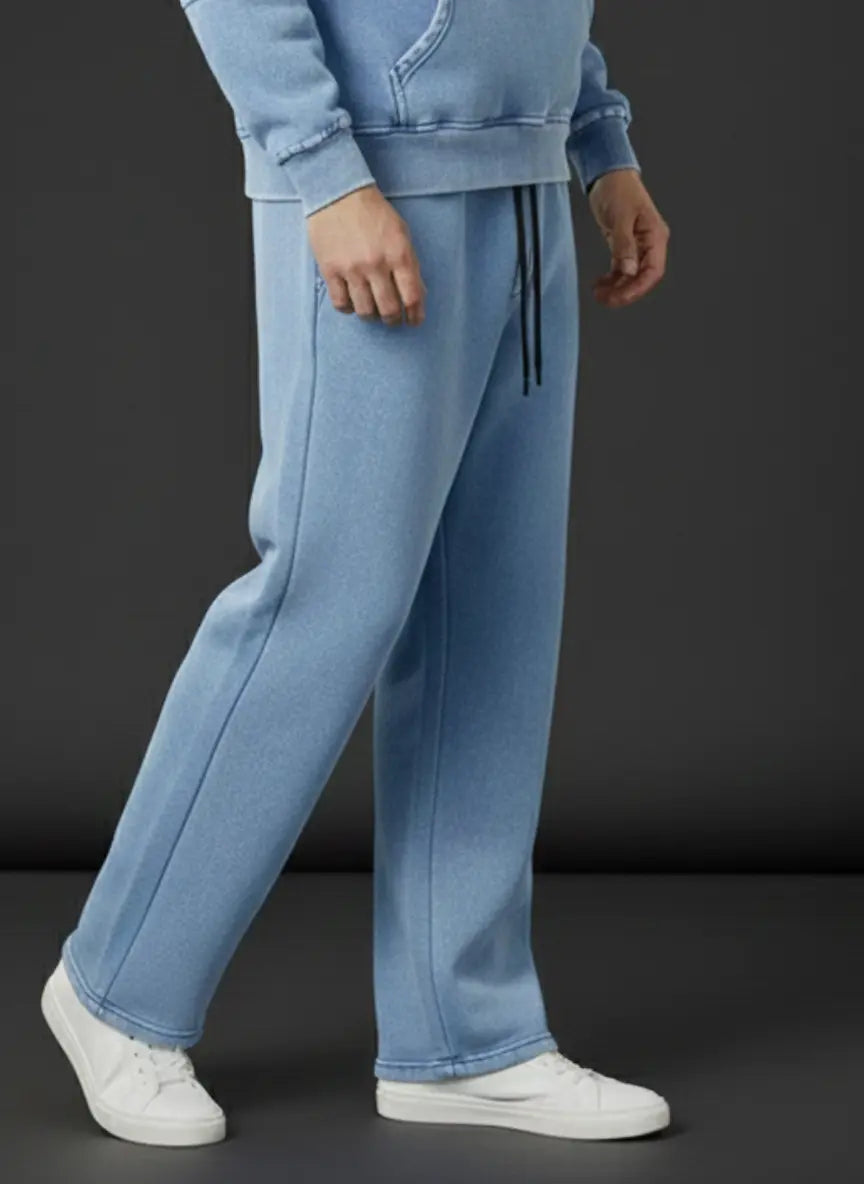 Person wearing light blue tracksuit with white sneakers on a black background