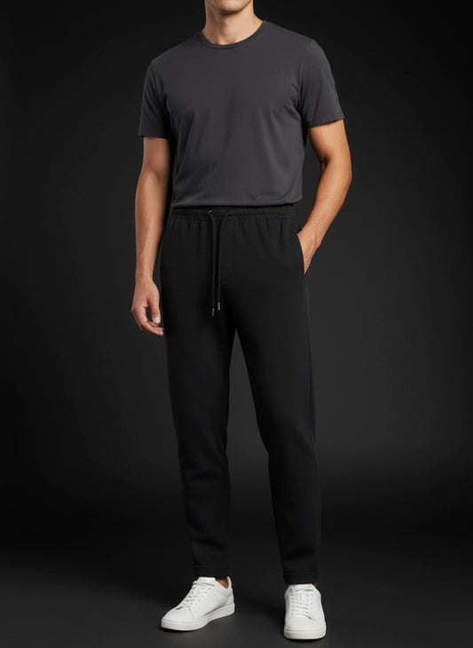 Person wearing a dark gray t-shirt and black pants with white shoes on a black background