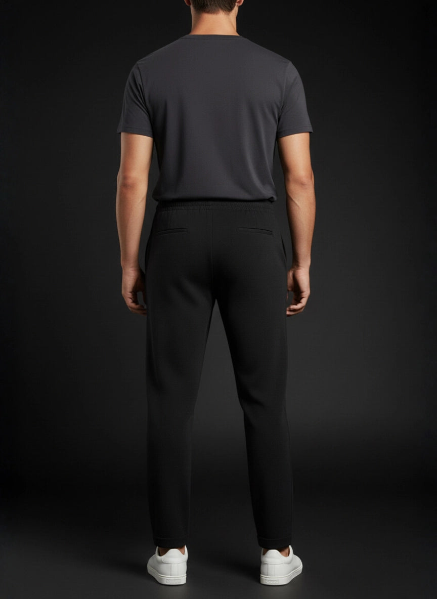 Person wearing a dark gray t-shirt and black pants on a black background